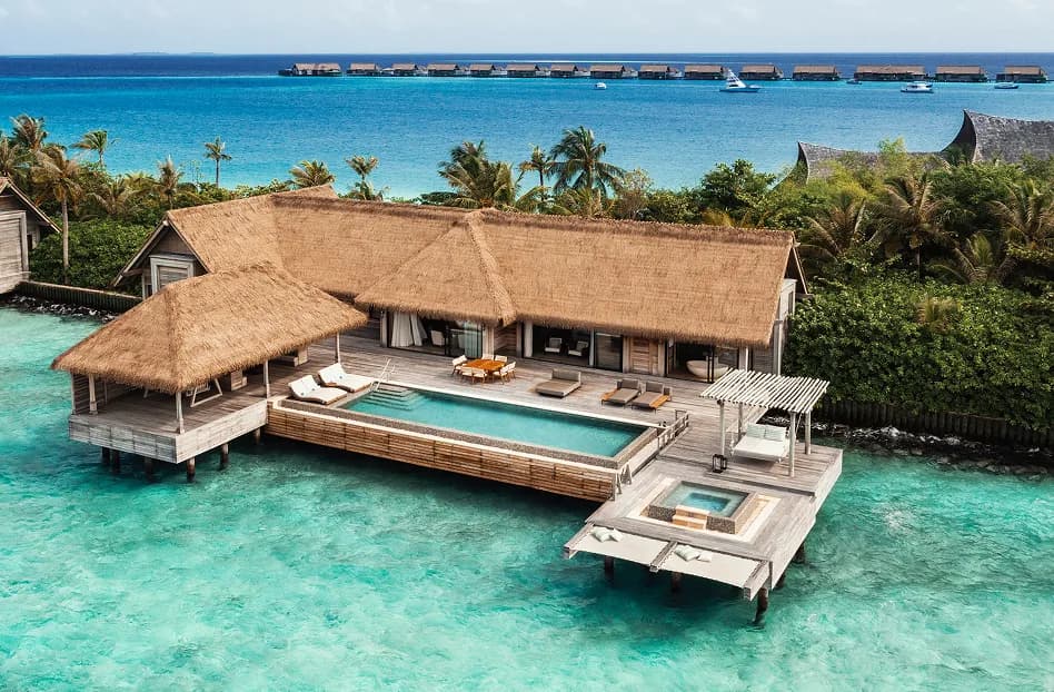 Aerial of a thatched over-water villa with private pool above the turquoise lagoon at Waldorf Astoria Maldives Ithaafushi