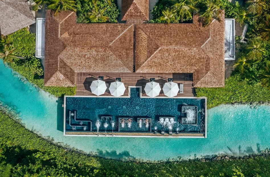 Aerial of a beach villa with a long private pool framed by tropical greenery at Waldorf Astoria Maldives Ithaafushi
