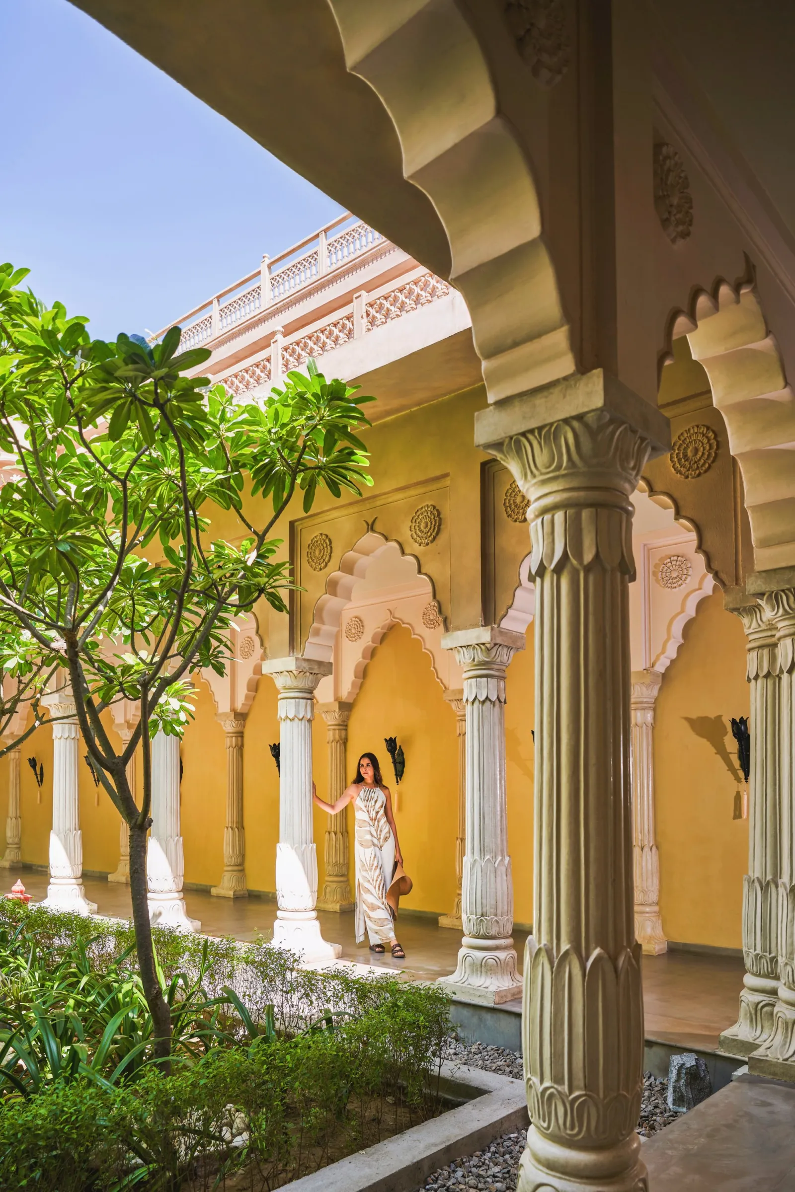 Aerial-style view of Fairmont Jaipur pink-sandstone Rajput fort and Mughal palace facade with chhatris near Amer Road