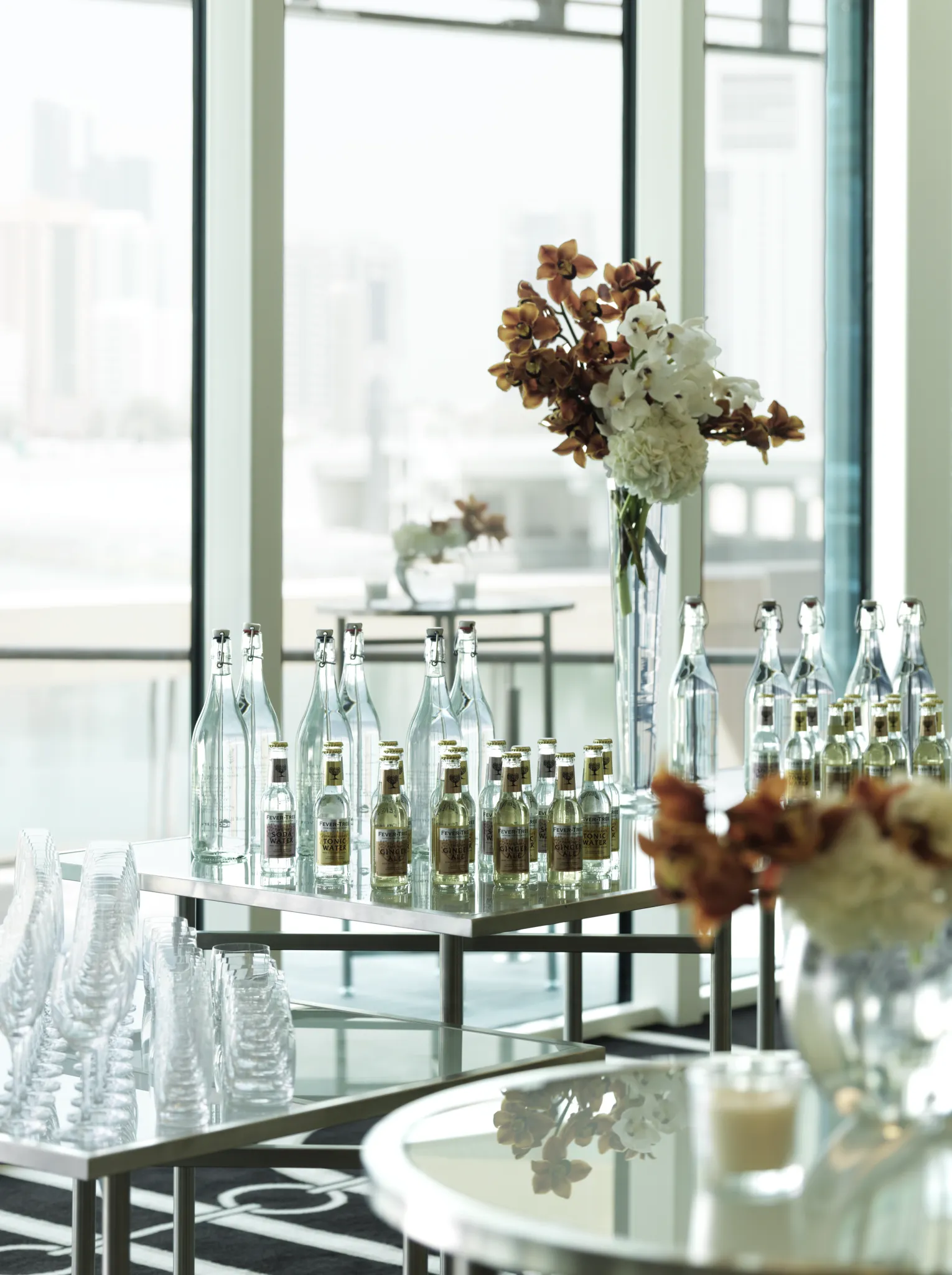 Decor welcome table with orchids and glassware against floor-to-ceiling skyline windows at Four Seasons Abu Dhabi
