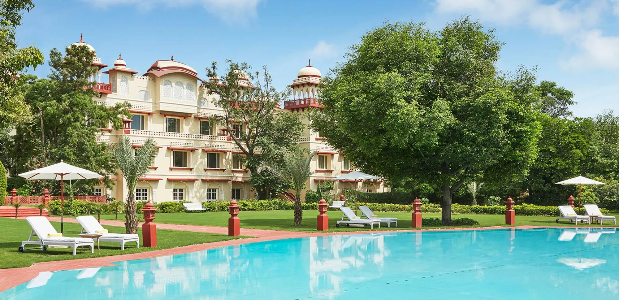 Poolside lawn with illuminated fountain and garden paths at Jai Mahal Palace Jaipur