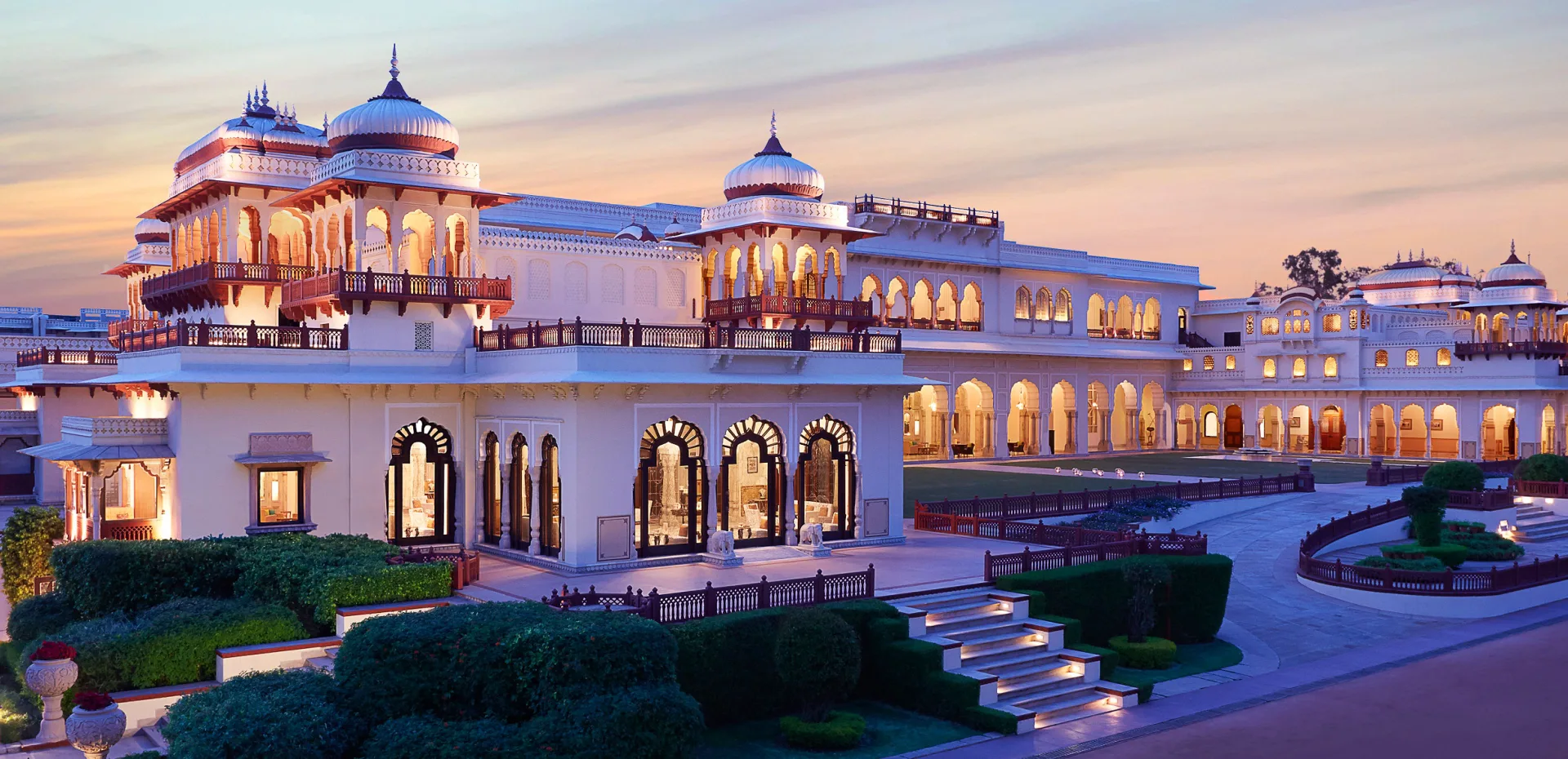 Rambagh Palace Jaipur symmetrical facade with cupolas and marble detailing against the Pink City sky