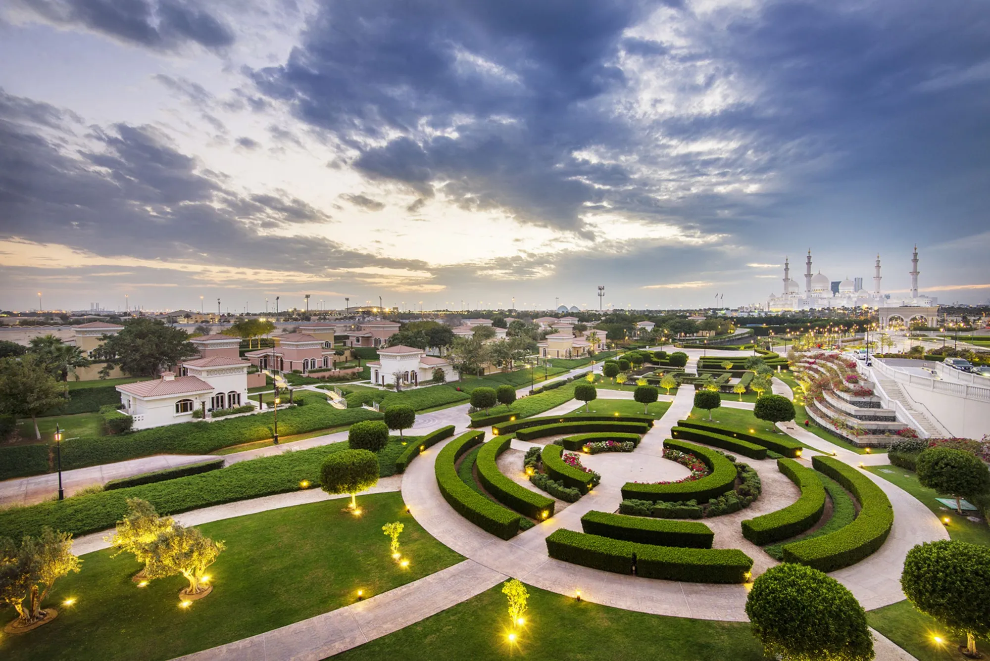 Manicured Venetian-style maze gardens at dusk with Sheikh Zayed Grand Mosque on the horizon at The Ritz-Carlton Abu Dhabi Grand Canal