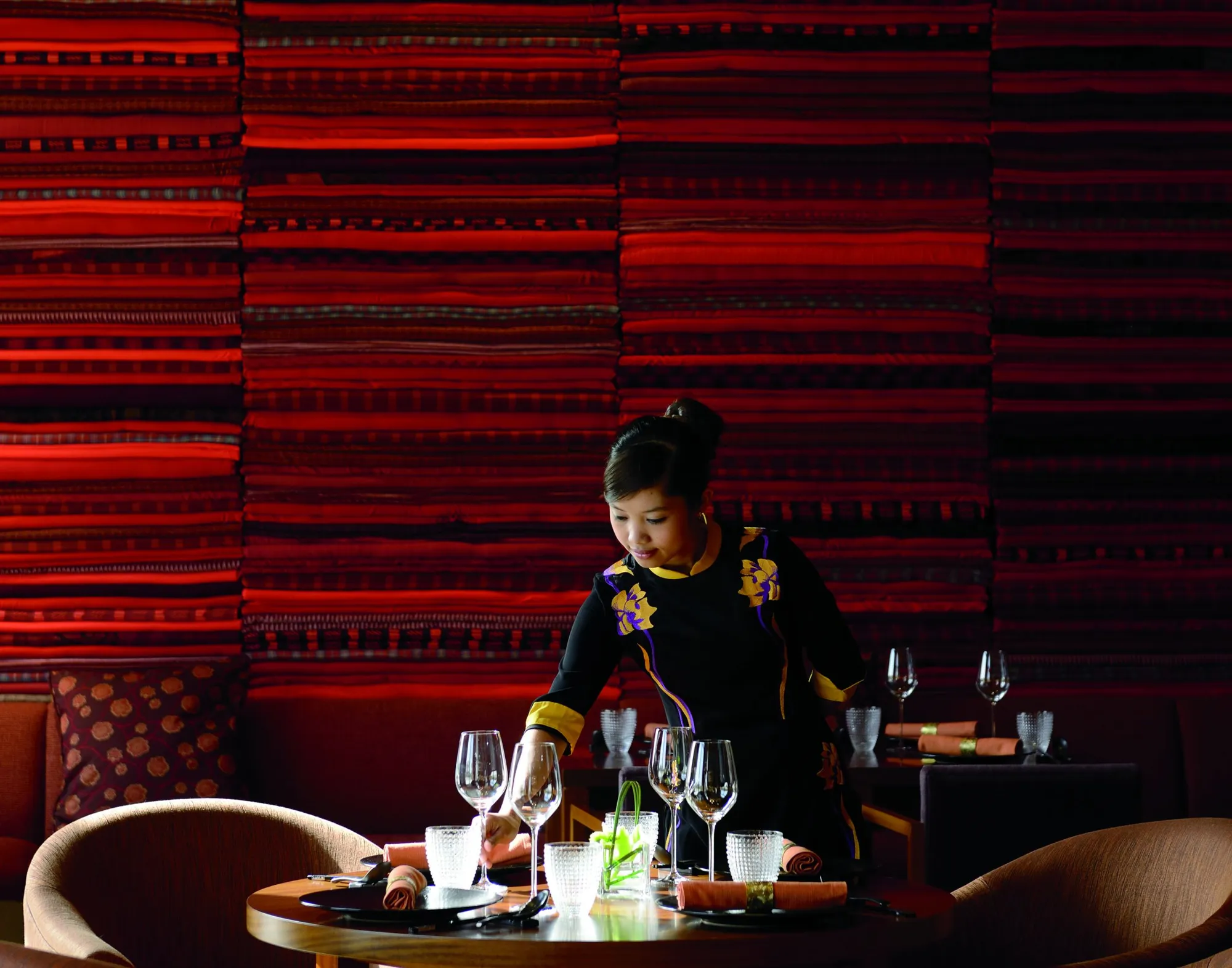 Server setting a fine-dining table against a textile wall at The Ritz-Carlton Abu Dhabi Grand Canal