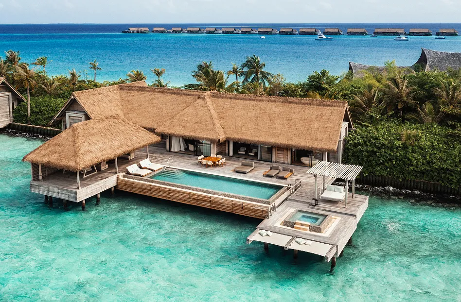 Aerial of a thatched over-water villa with private pool above the turquoise lagoon at Waldorf Astoria Maldives Ithaafushi